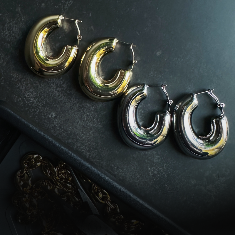 two pairs of earrings on work surface with jewelry pliers