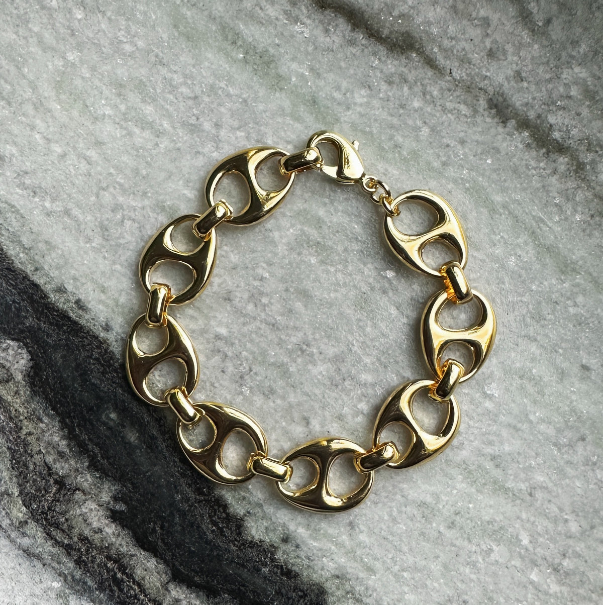 Gold chain link bracelet from COCOA ARI demi-fine jewelry on marble background