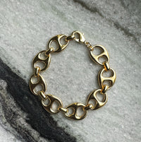 Gold chain link bracelet from COCOA ARI demi-fine jewelry on marble background