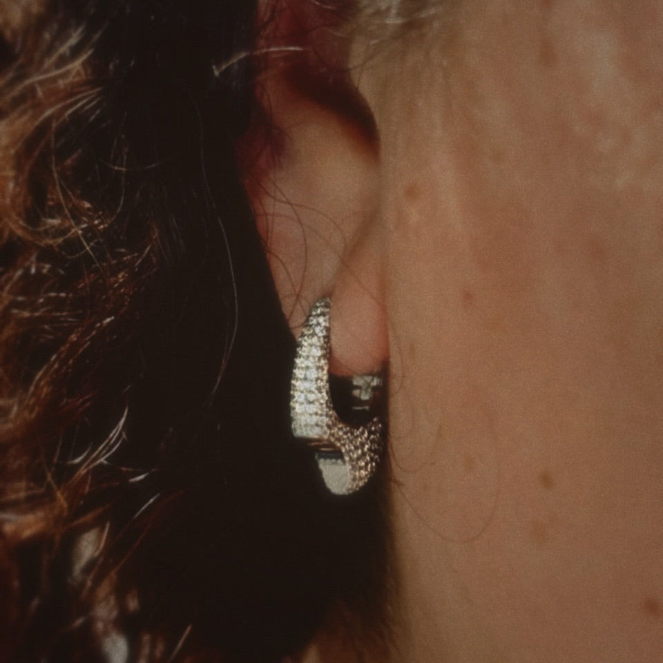 Close-up of an ear wearing a diamond hoop earring.