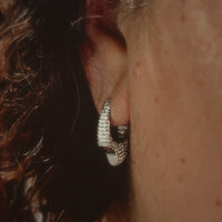 Close-up of an ear wearing a diamond hoop earring.