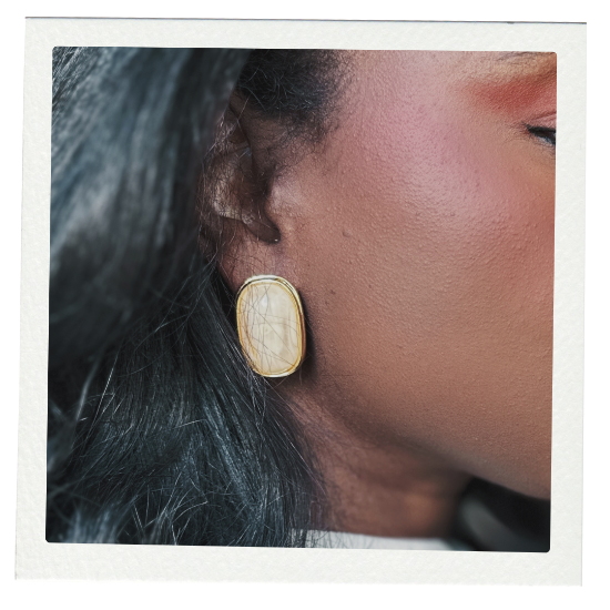 Close-up of a gold earring with large ivroy stone on a model