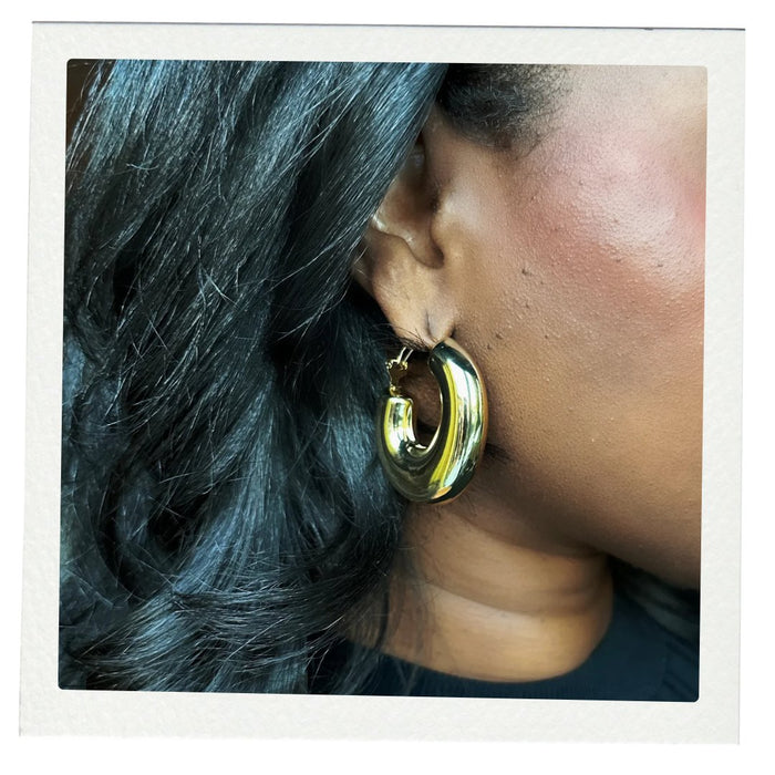 Close-up of a woman's ear wearing a bold gold Cocoa Ari Avenue earring, modern demi-fine jewelry