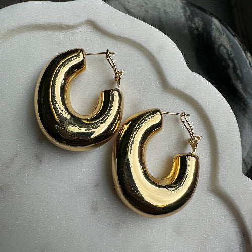 Gold hoop earrings on a marble surface