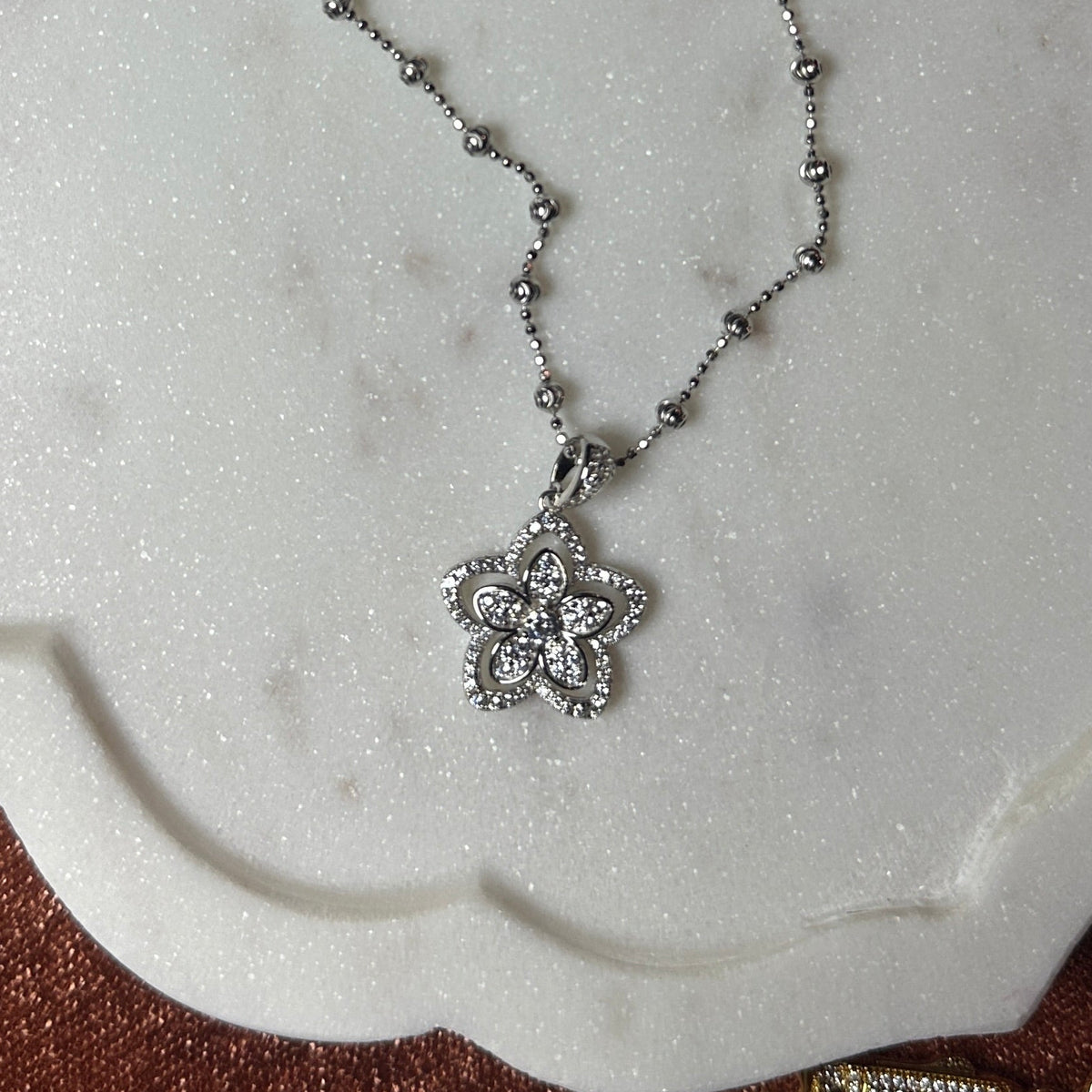 Silver necklace with a pendant on a marble surface