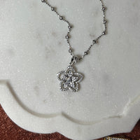 Silver necklace with a pendant on a marble surface