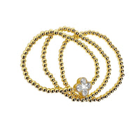 Set of gold beaded bracelets with a heart-shaped clasp on a white background