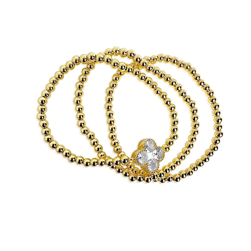 Set of gold beaded bracelets with a heart-shaped clasp on a white background