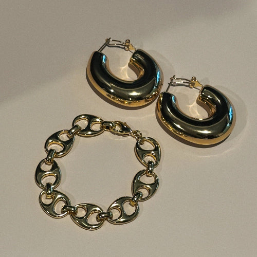Gold hoop earrings and bracelet on a light gray background