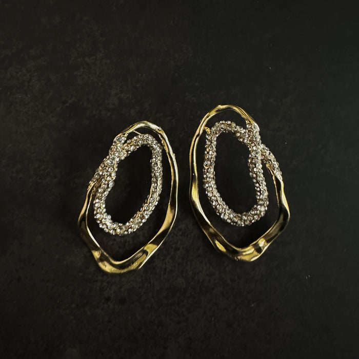Gold hoop earrings with embedded pavé stones on a dark background