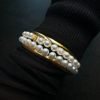 Smooth gold bracelet with pearls as teeth with gold tooth on wrist