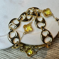 Gold bracelet with green gemstone charms on a textured surface