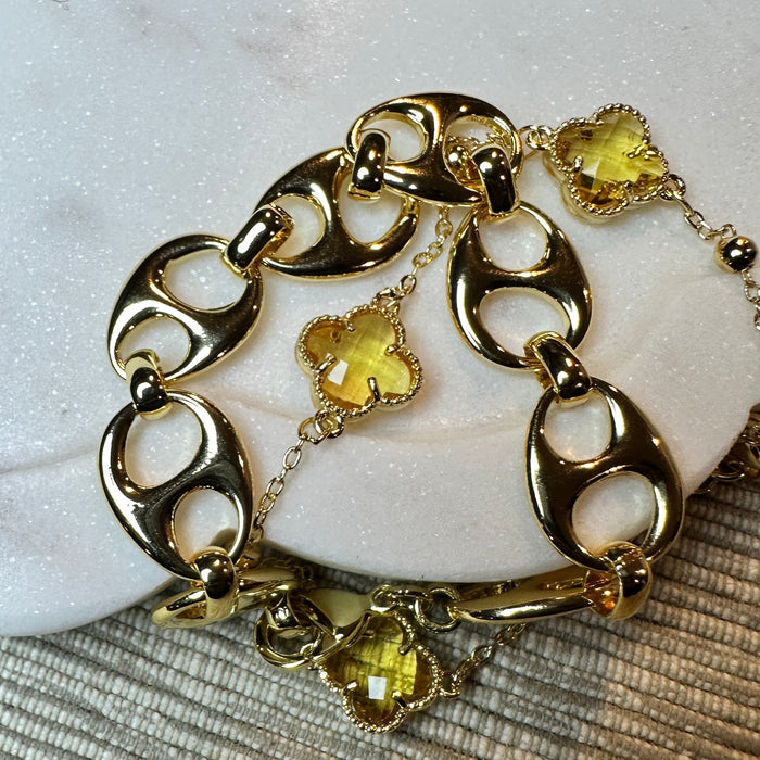 Gold bracelet with green gemstone charms on a textured surface