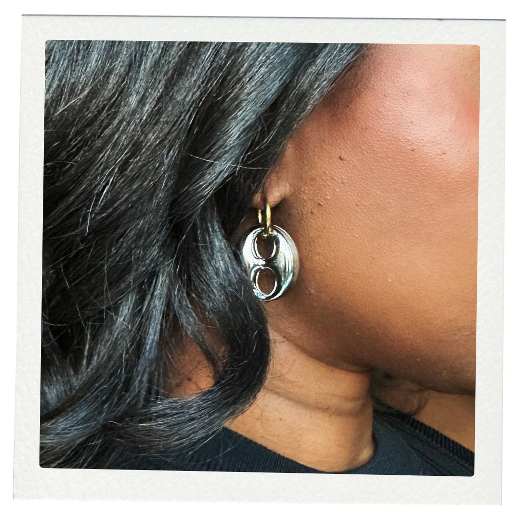 Close-up of a person wearing a silver mariner earring with a gold accent.