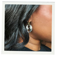 Close-up of a person wearing a silver mariner earring with a gold accent.