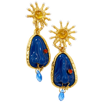 Pair of earrings with a sunburst and blue nose with blue stones and gold accents on a white background