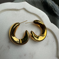 Gold hoop earrings on a textured white surface