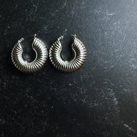 Pair of silver hoop earrings on a dark textured surface