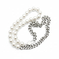 Pearl necklace and silver chain on a textured surface