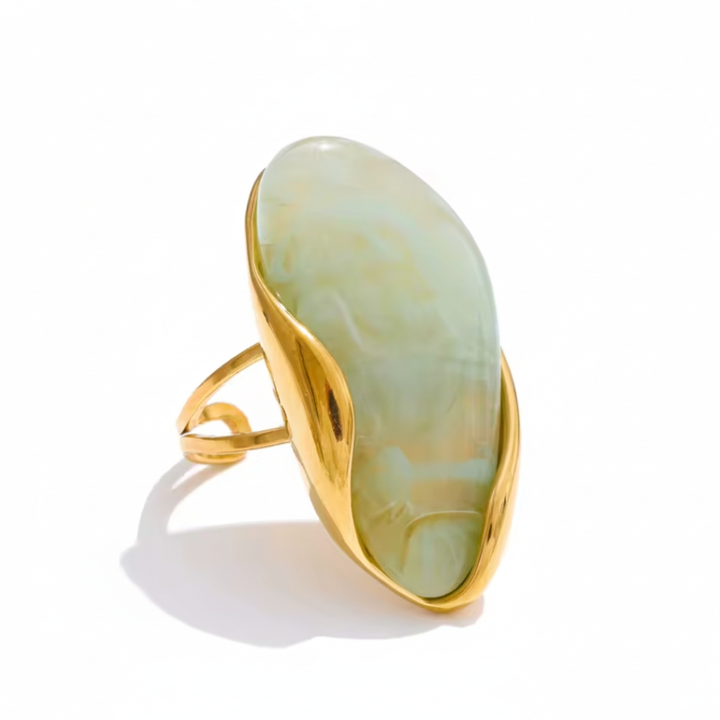 cocoa ari ring with a gold band and light green stone on a white background