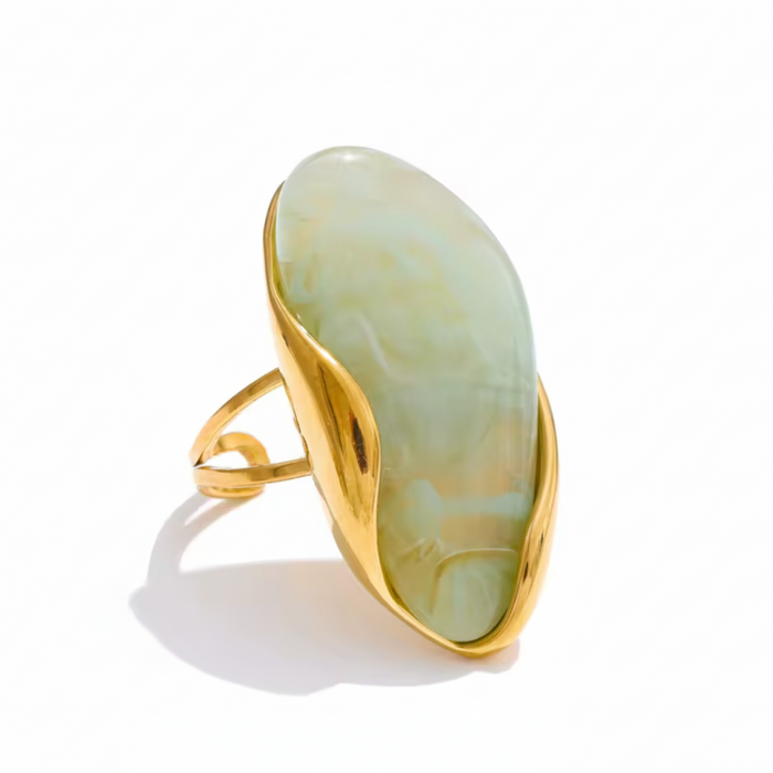 cocoa ari ring with a gold band and light green stone on a white background
