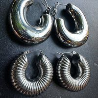 Pair of silver hoop earrings on a dark surface