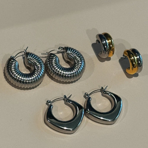 Set of silver and gold hoop earrings on a beige background