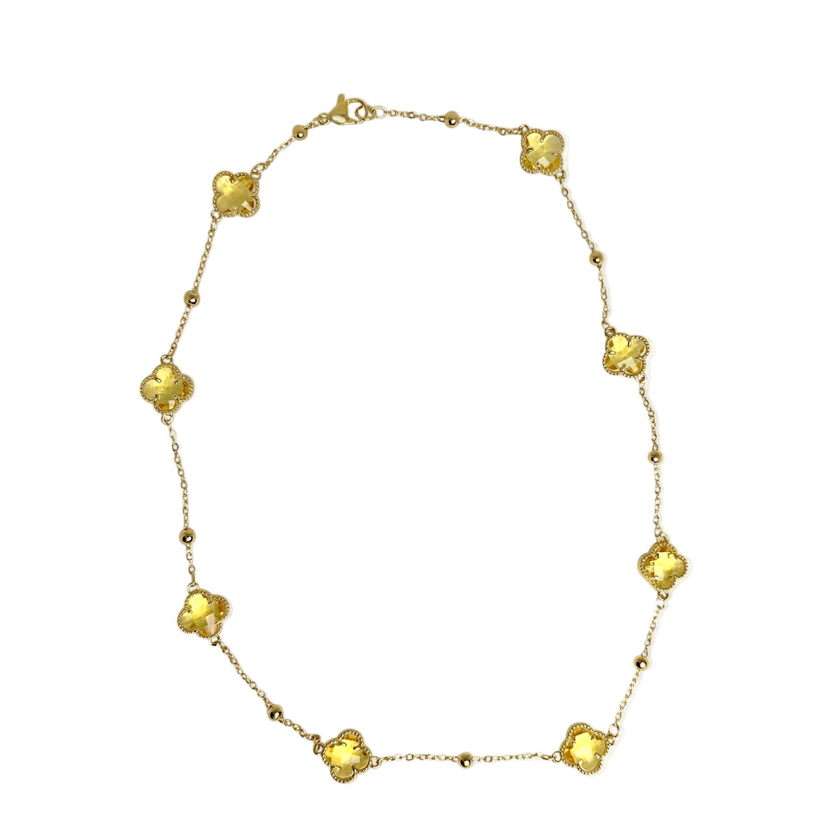 Gold station necklace with yellow crystal clover motif stones white background