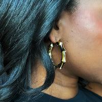 Gold bamboo-style hoop earring by COCOA ARI worn on ear, demi-fine jewelry close-up