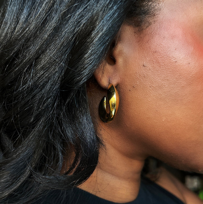 Gold demi-fine Cocoa Ari Luna Melt earring on ear, modern jewelry design, close-up